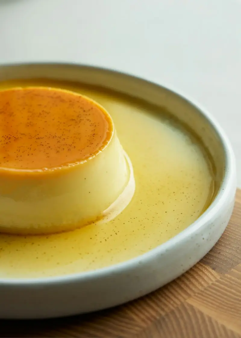 Crème caramel individual desenformado num prato fundo, com a calda clara de caramelo em volta